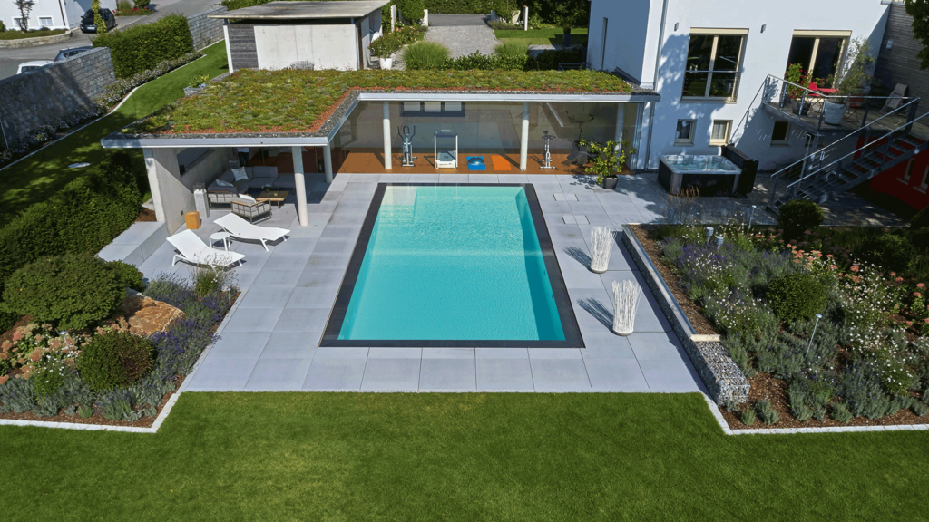 Blick von oben auf den Pool, den Garten und das Wohnhaus mit überdachtem Patio.