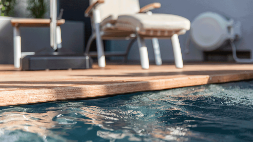 Schwimmbeckenrand mit einer hölzernen Terrasse und einem Liegestuhl.