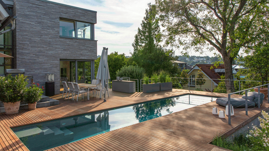 Einfamilienhaus mit modernem Pool umgeben von einer hölzernen Terrasse und mit gutem Ausblick.