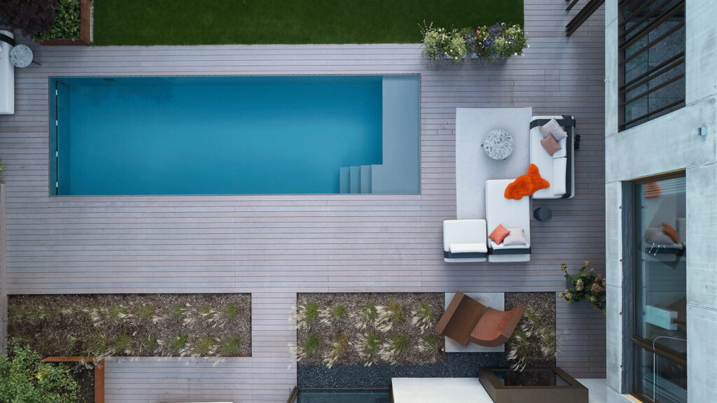 Ein Pool von einer Holzterrasse umgeben mit gut erkennbarerer Einstiegstreppe und Flachwasserzone aus der Vogelperspektive.