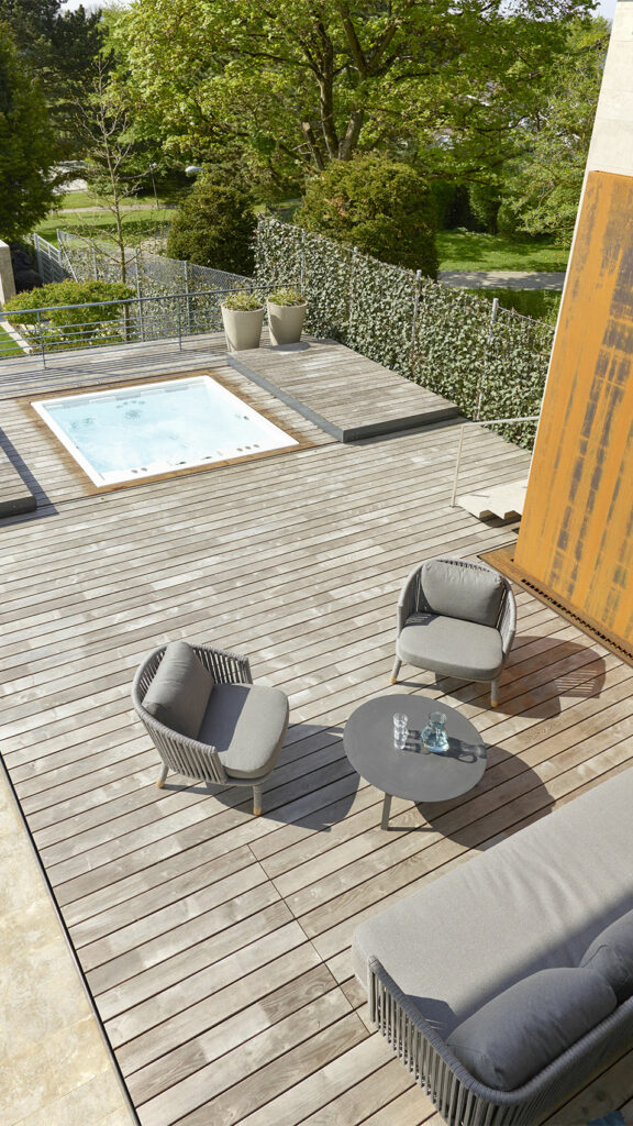 Blick von oben auf eine Holzterrasse mit eingelassenem Whirlpool und Sitzlounge.