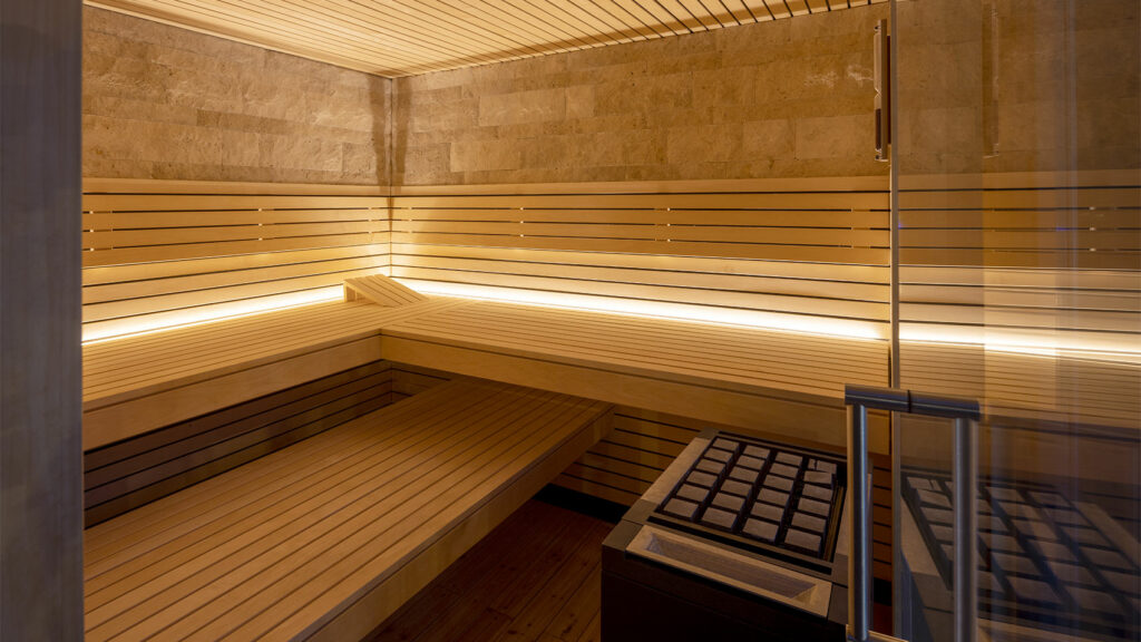 Blick in eine moderne Sauna mit Holzbänken und gemütlicher warmweißer Beleuchtung.